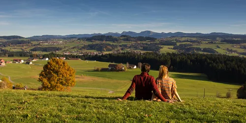 Mann und Frau auf grüner Wiese mit Blick auf Hügel