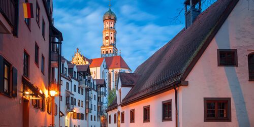 In den Gassen einer Altstadt mit Blick auf einen Kirchturm im Hintergrund