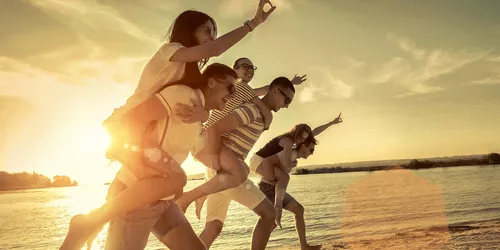 Junge Menschen beim Huckepack am Strand